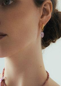 Kvinde med hoops og charms i guldbelagt sterling sølv fra carré jewellery med en stor ametyst charm i guld 