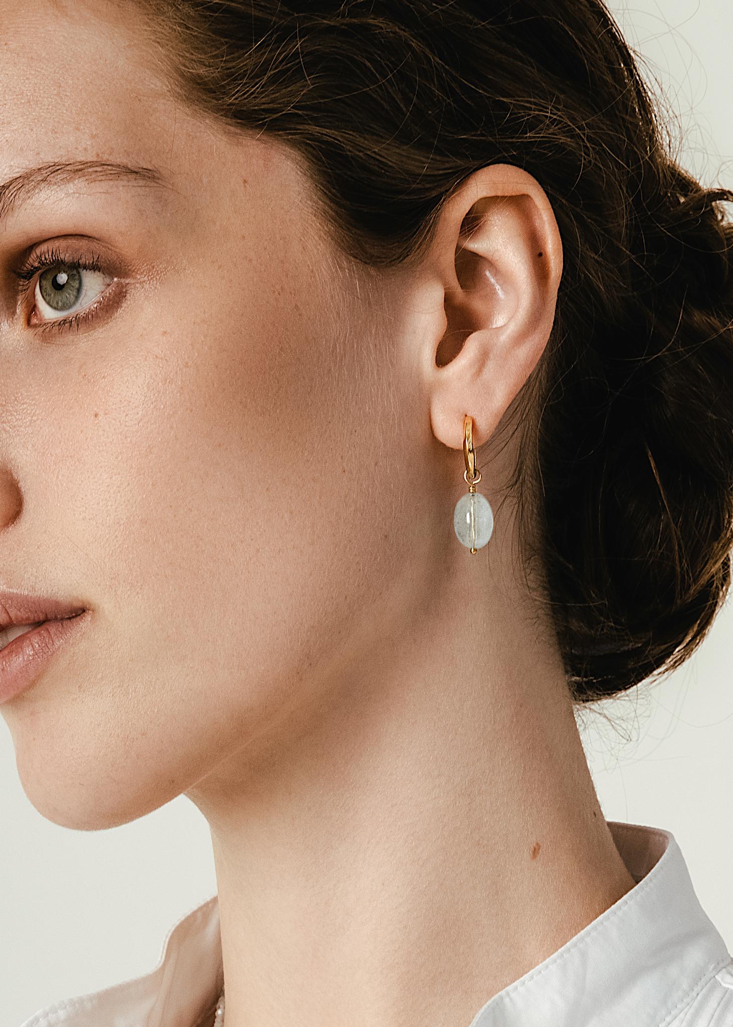 Kvinde med 1,5 cm twist hoop fra carré jewellery med en akvamarin charm til mænd og kvinder i guldbelagt sterling sølv 