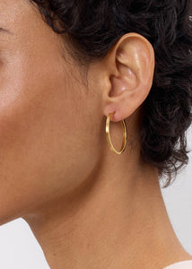 Ung kvinde med store creol hoops fra carré jewellery i 3 cm i guldbelagt sterling sølv med unikke detaljer i tyndt og elegant design på tilbud lige nu 