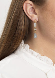 Woman with gold dangling ear studs with mixed gemstones in Danish design