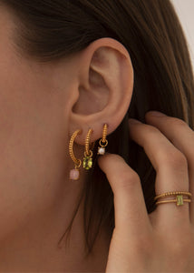 Kvinde med hoops og charms fra carré jewellery i guld med perler og grønne sten 