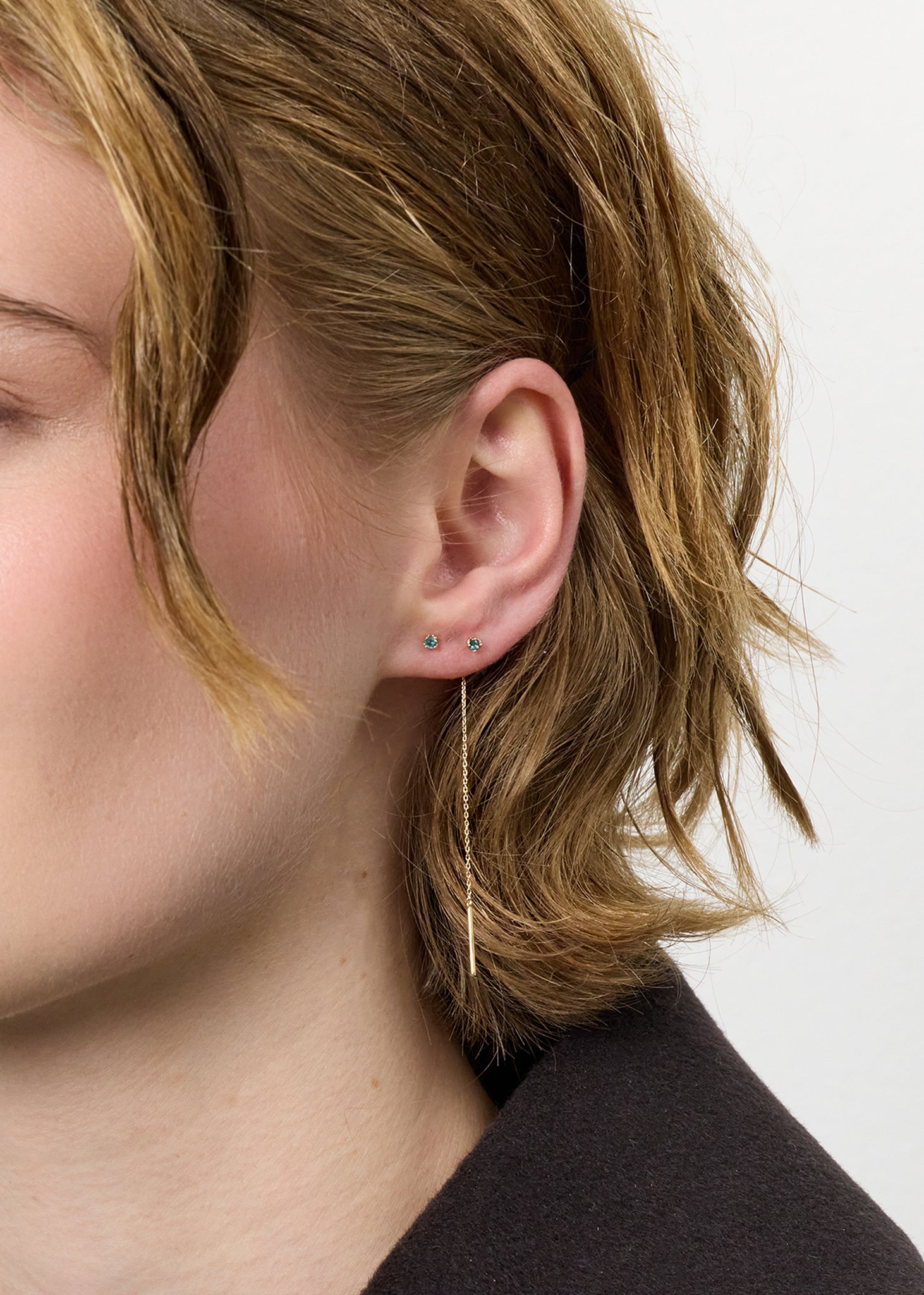 kvinde med lange hængeøreringe, der trækkes gennem øret i ægte 10k guld med london blå topas ædelsten