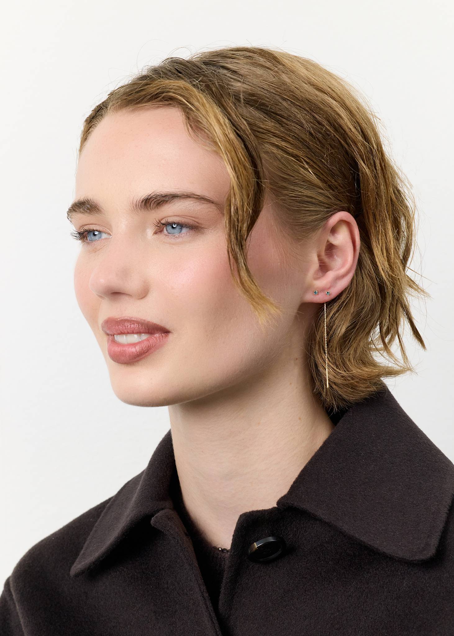 Ung kvinde med lange kædeøreringe i 10 karat guld med novembers fødselssten london blå topas 