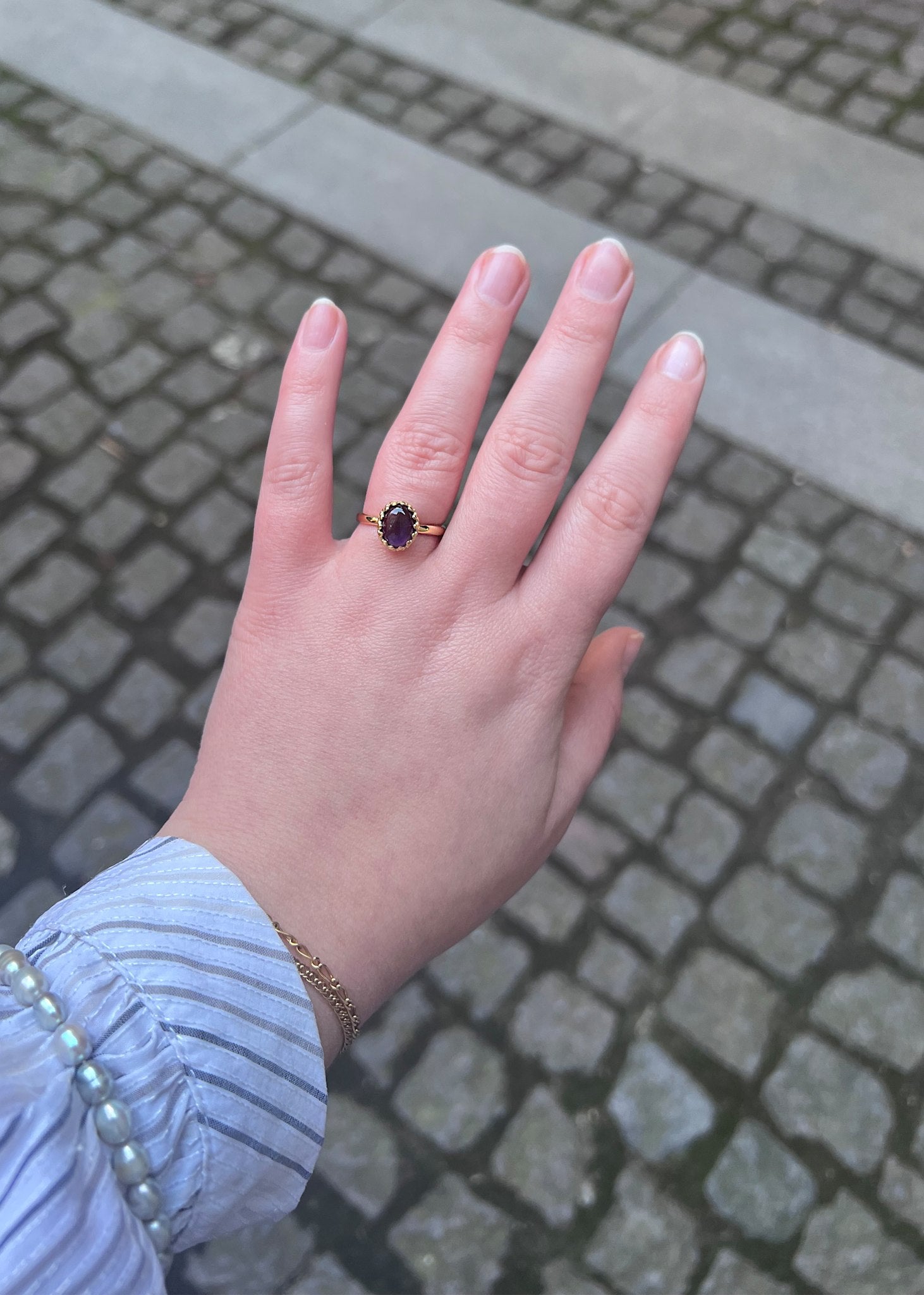 Kvindehånd med elegant ametyst ædelstens ring i en blondekant i guldbelagt sterling sølv